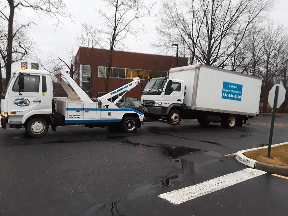 A tow truck is parked in front of a building, ready to assist with vehicle removal or roadside service.